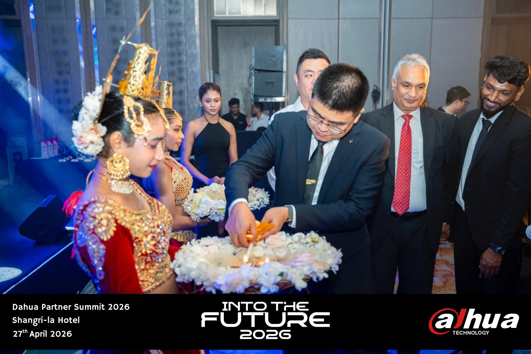 Guest of honour lighting the traditional oil lamp, welcomed by dancers in red and gold Kandyan dress